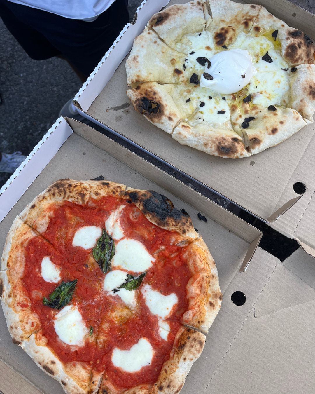 A margherita and a burrata pizza fresh out of the oven in their boxes